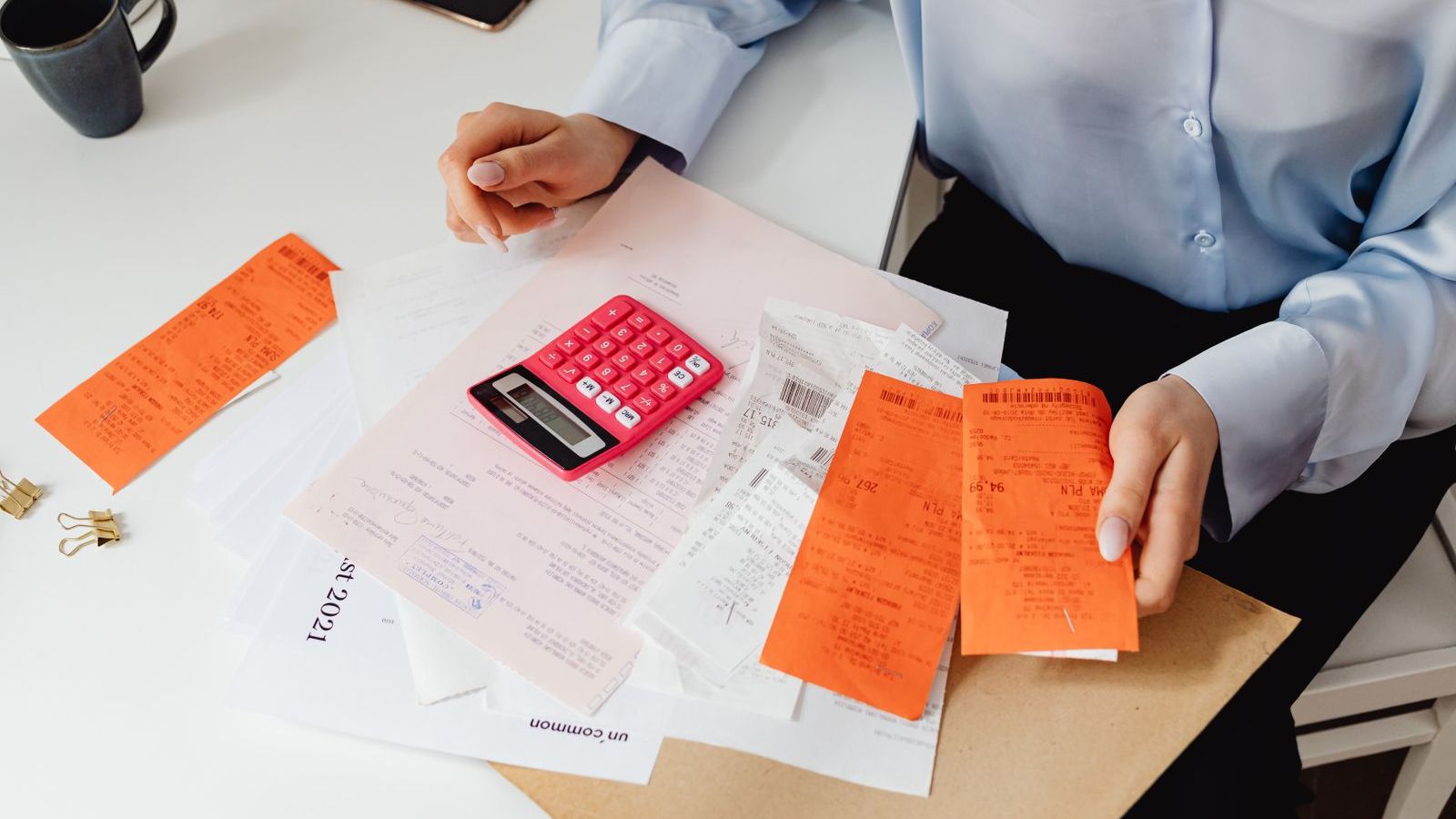 Person holding paper receipts and using a calculator, representing employee expense claims for field teams
