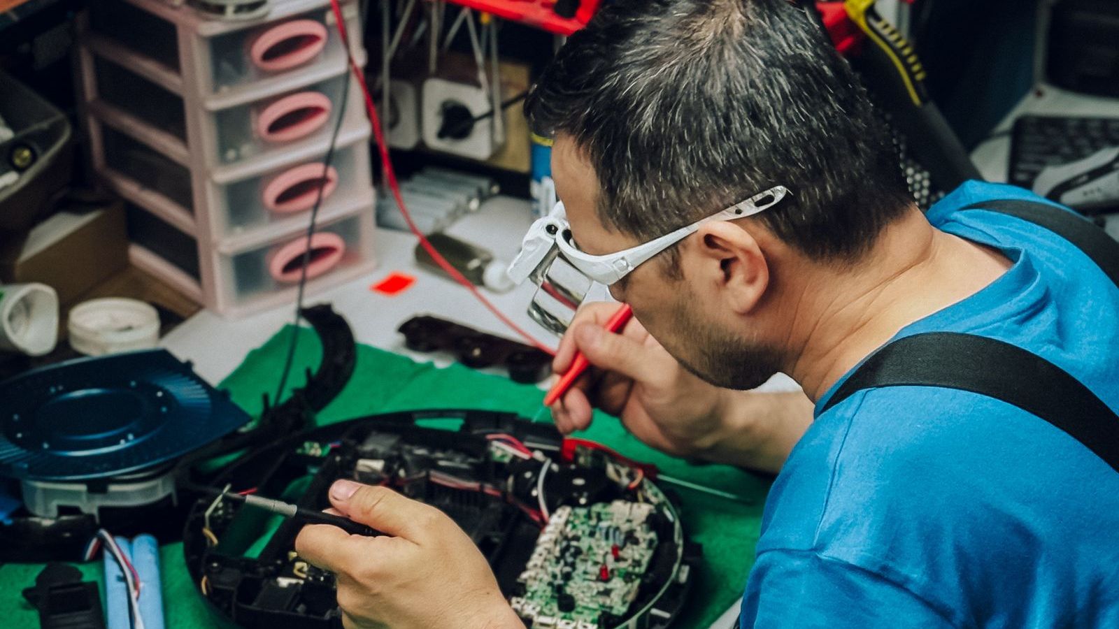 Technician repairing an electronic device at a workbench, representing field service and repair work