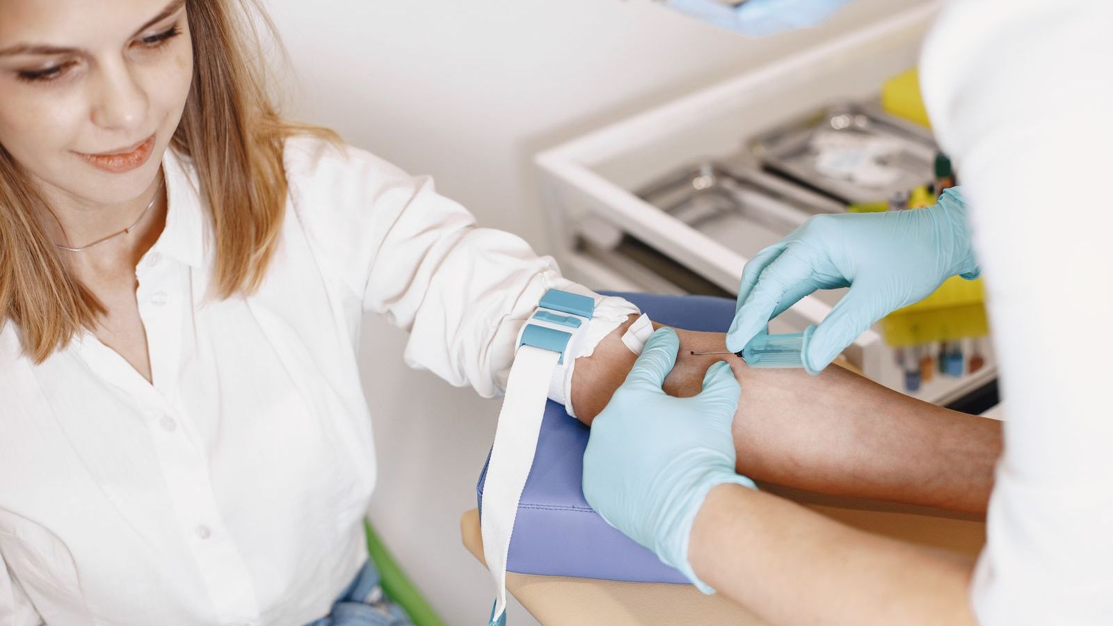 Health worker taking a blood sample from a patient's arm, representing home sample collection visits
