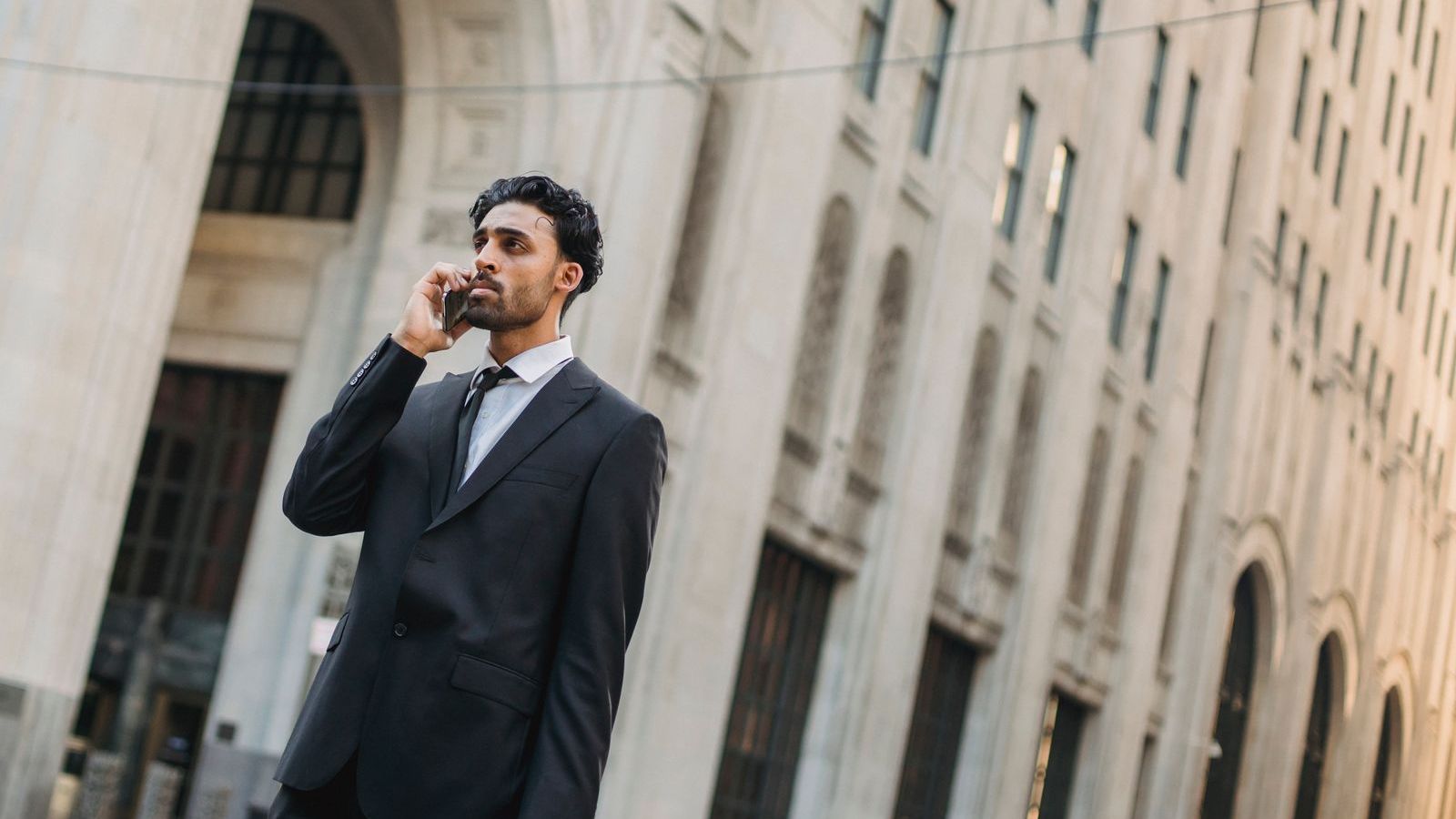 Businessman on a phone call outdoors in a city, representing a manager checking in with field sales staff