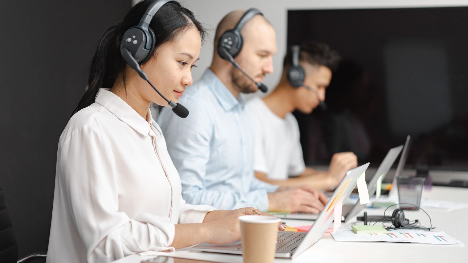 Customer support team wearing headsets at desks, representing handling and reducing service complaints
